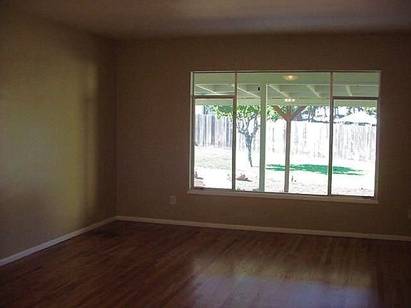 Spacious living room overlooks covered patio and park like backyard.