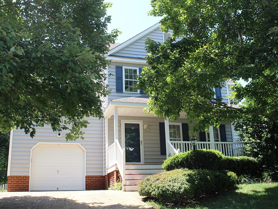 Frontal home view - Colonial style home with single car garage, porch, two-car driveway flanked by lovely landscape.