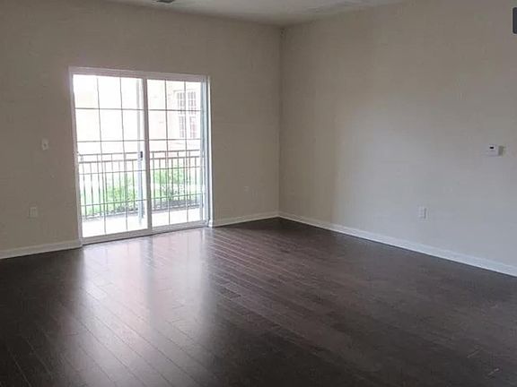 Living room with hardwood floors. Sliding door into patio/balcony.