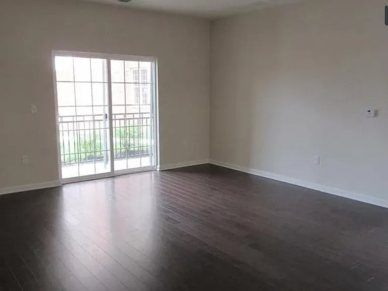 Living room with hardwood floors. Sliding door into patio/balcony.