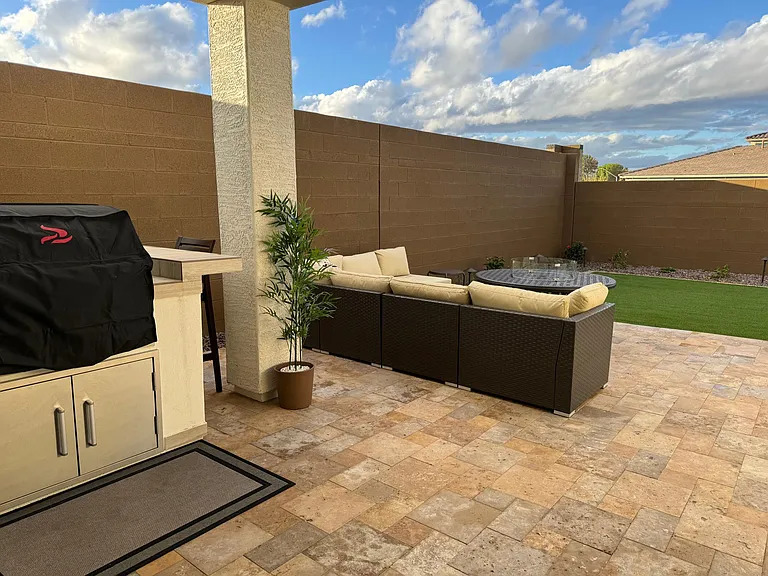 Back yard- built in bbq with bar seating, couch with firepit. Yard with turf and shrubs along the perimeter