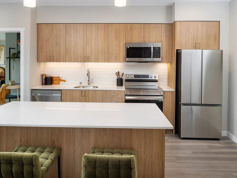 Kitchen with oak cabinetry, stainless steel appliances, granite countertops, and hard surface flooring - Avalon Redmond Campus