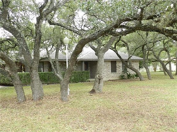 Front of the home with wrap around porch and gorgeous trees