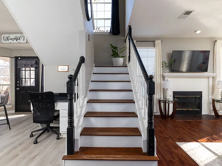 Modern open-plan living room with an elegant staircase and warm wood flooring.