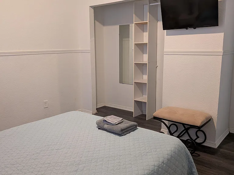 Wall-mounted TV, and shelving in closet plus a extra seating.