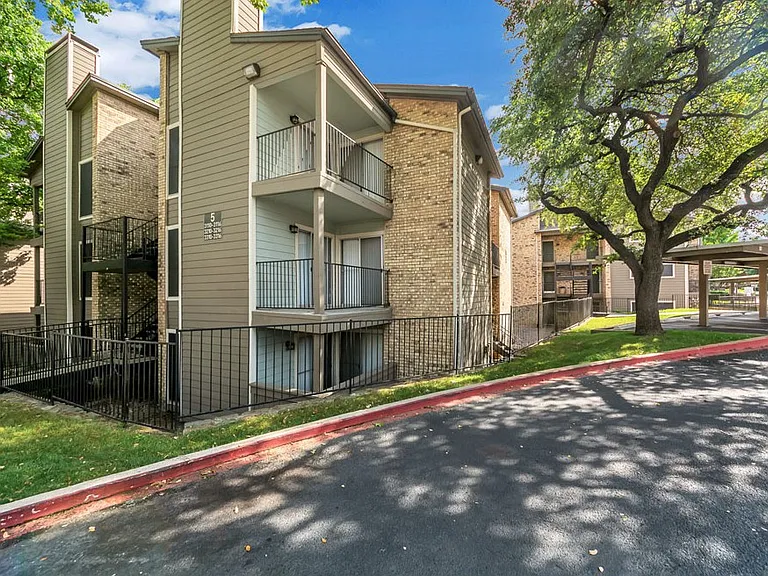 Exterior apartment buildings with mature landscaping and shaded walkways