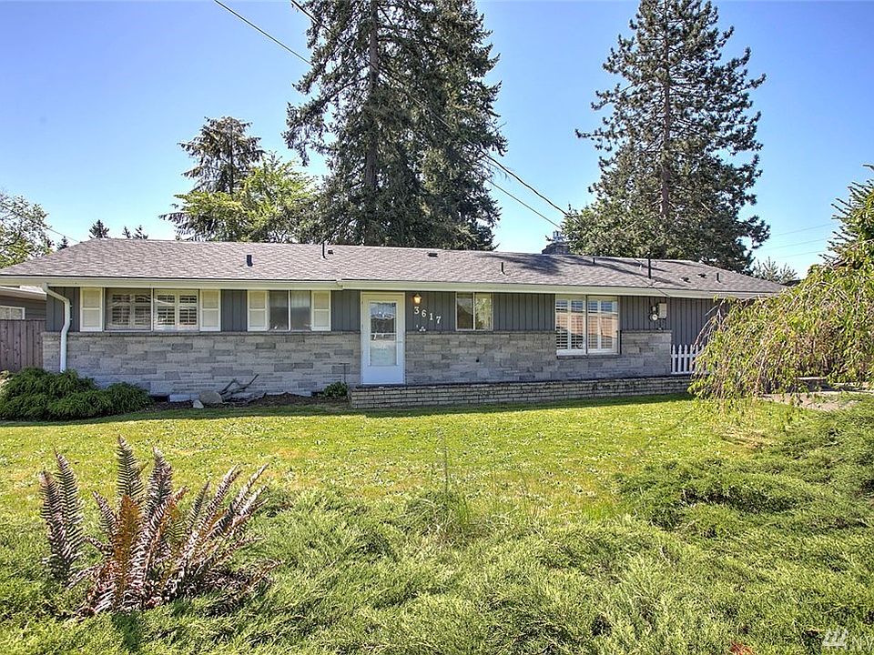 Welcome home to Kent's West Hill! This charming 3 bedroom, 2 bath rambler features bright open spaces, lovely hardwood floors and a large back yard for gathering with friends. The spacious living room is sure to delight with a gorgeous gas fireplace, a wall of windows and large slider to the entertainment sized patio where you can extend your gatherings outside to the expansive, fully fenced backyard featuring mature trees, two outbuildings, a play structure and room to run. One of the outbuildings is a large detached garage! The sunny kitchen provides lots of storage space and is open to the charming informal dining room. The main living areas and guestrooms feature gleaming hardwood floors, and nearly all the windows have beautiful plantation shutters. The bathroom has a deep jetted tub and dual vanity. This home also features a large unfinished space with continental access to a full bathroom--ideal for conversion into a guest suite, home office, media or hobby space. 
