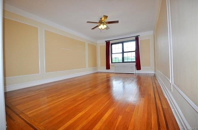 Large Sunny living room with a cove ceiling, wall and picture molding and refinished hardwood floors