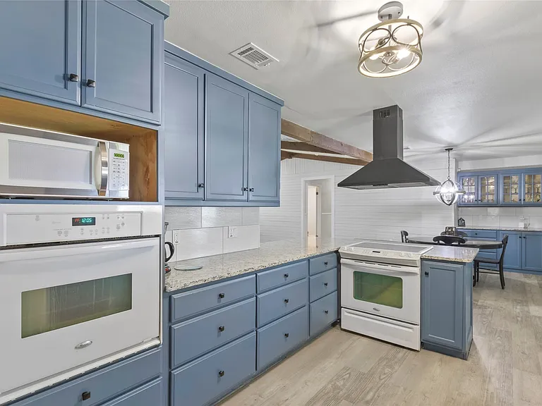 Kitchen with blue cabinetry, light-colored countertops, and wood-finish flooring
