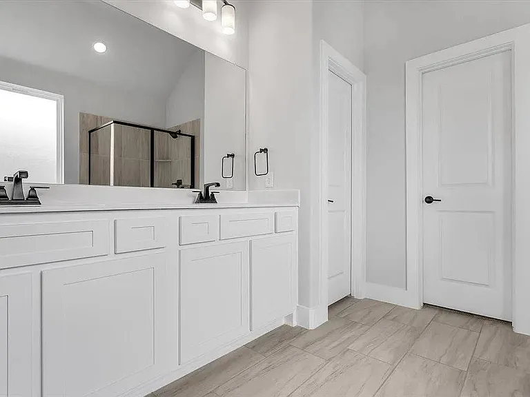 Dual sink vanity featuring white cabinetry, light-toned countertops, and matte black fixtures