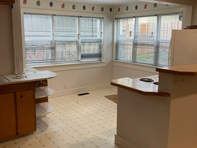Sunny kitchen with refrigerator, stove, storage