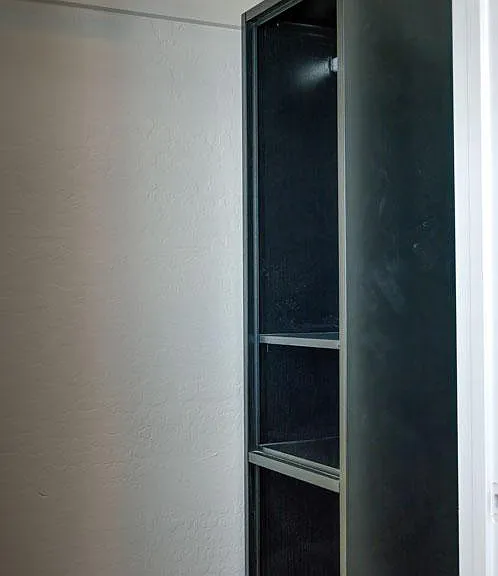 Built-in storage cabinet with open shelving provides convenient space for linens, supplies, or personal items.