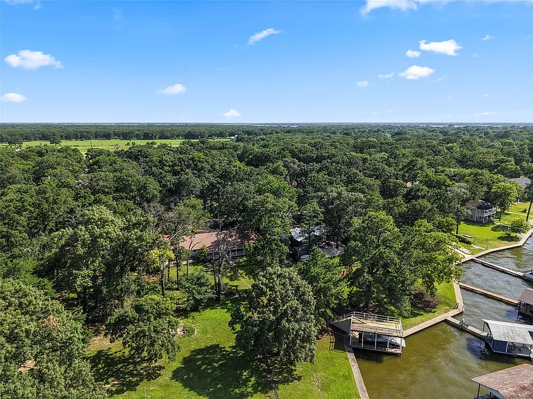 Waterfront property featuring a private boat dock, lush green surroundings, and mature trees