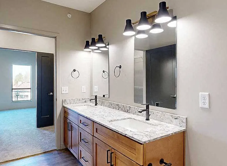 Indulge in luxurythe primary bathroom of our two-bed Meadow boasts a double vanity, elegant fixtures, and a modern aesthetic.