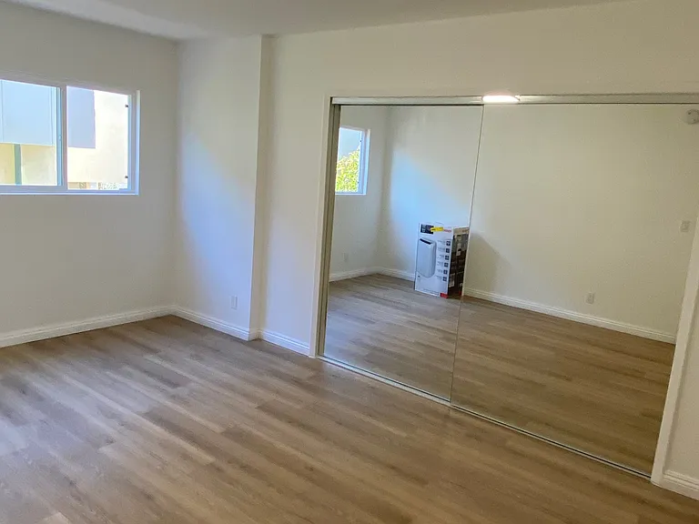 Bedroom has wall to wall closet with mirrored doors.