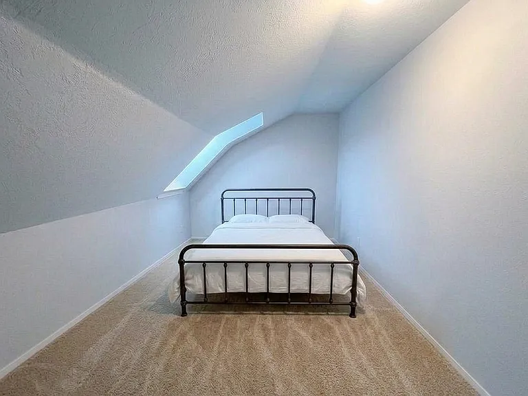 Bright upper-level bedroom featuring a comfortable queen bed.