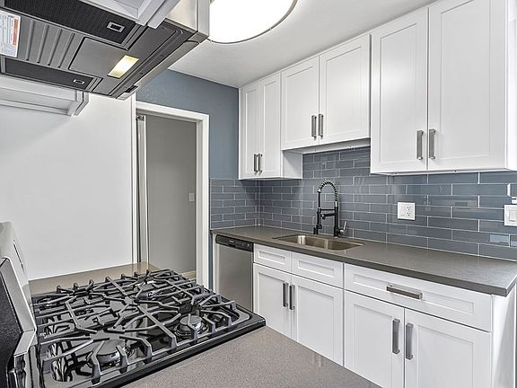 Kitchen with blue tile backsplash and stainless steel Stove, Oven, and fixtures.