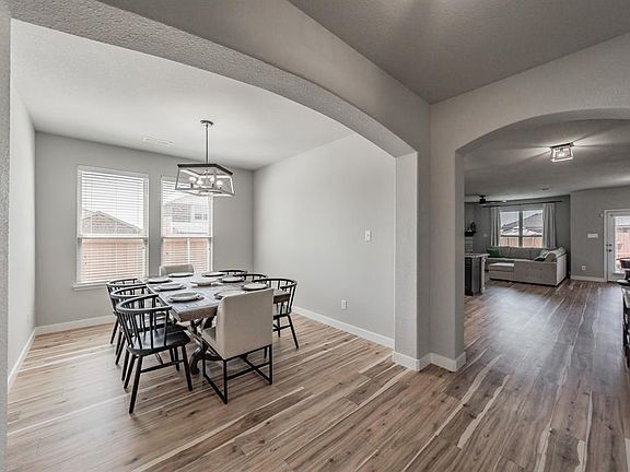 Dining area featuring arched walkways, light wood-style floors, and a ceiling fan