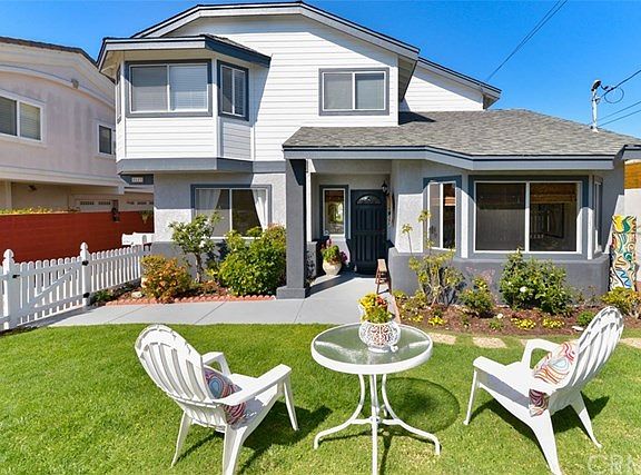 The front of the home with newly painted trim, exterior, and front door as well as new landscaping,