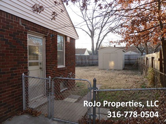 Spacious fenced backyard with large shed for extra storage.