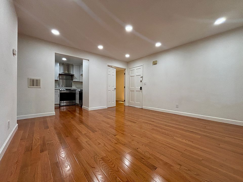 A view from the balcony, seeing the living room, kitchen, small bedroom, and front door of the condo.