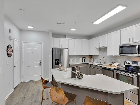 Modern kitchen with sleek stainless steel appliances, stylish white cabinetry, and elegant countertops, ideal for contemporary living.