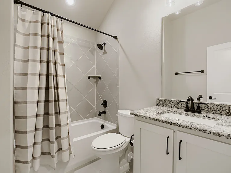 Bathroom featuring a white vanity with a granite countertop, integrated sink, and matte black fixtures