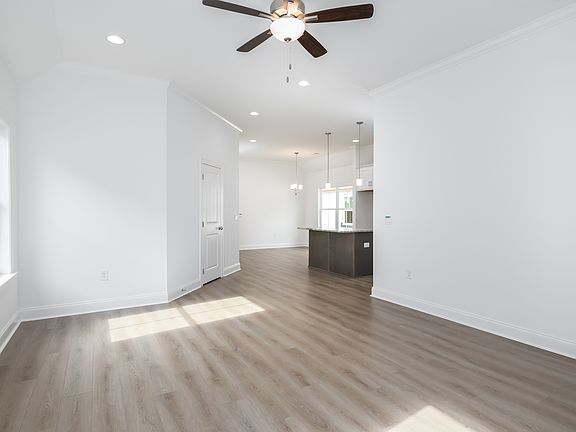 Open-concept living area with wood-look flooring, high ceilings, and views into the kitchen