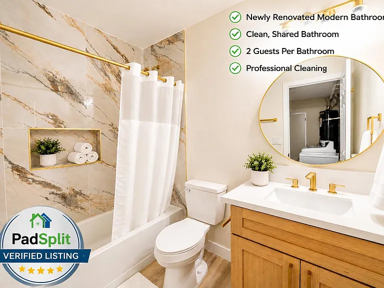 Updated shared bathroom with a tub/shower combo, tiled surround, and a wide vanity with storage and an oversized mirror.