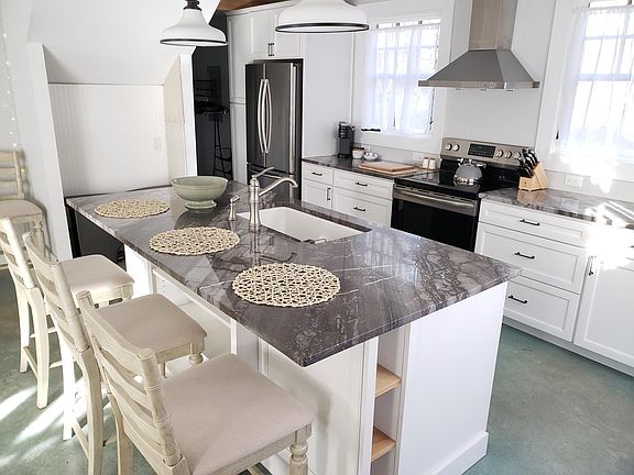 The stainless steel appliance suite includes a full size french door refrigerator, flat top electric stove. exhaust hood and dishwasher.