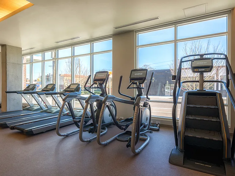 Cardio room with large windows and premium machines for energizing workouts.