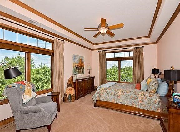 Spacious corner master suite with lake views, walk-in closet, trayed ceilings, crown moulding, and sitting area