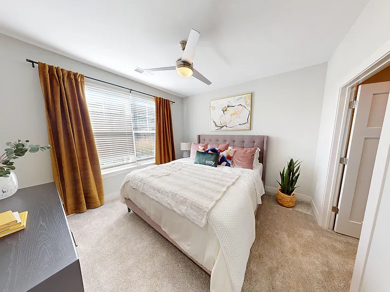 The Oaks bedroom features lush carpet, large windows with natural light, overhead lighting with a ceiling fan, and a walk-thru closet. The Oaks bedroom features lush carpet, large windows with natural light, overhead lighting with a ceiling fan, and a wal