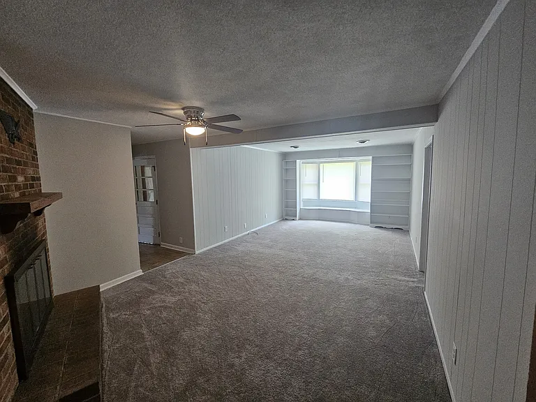Family room with new paint, new carpet, ceiling fan and built in bookcases.