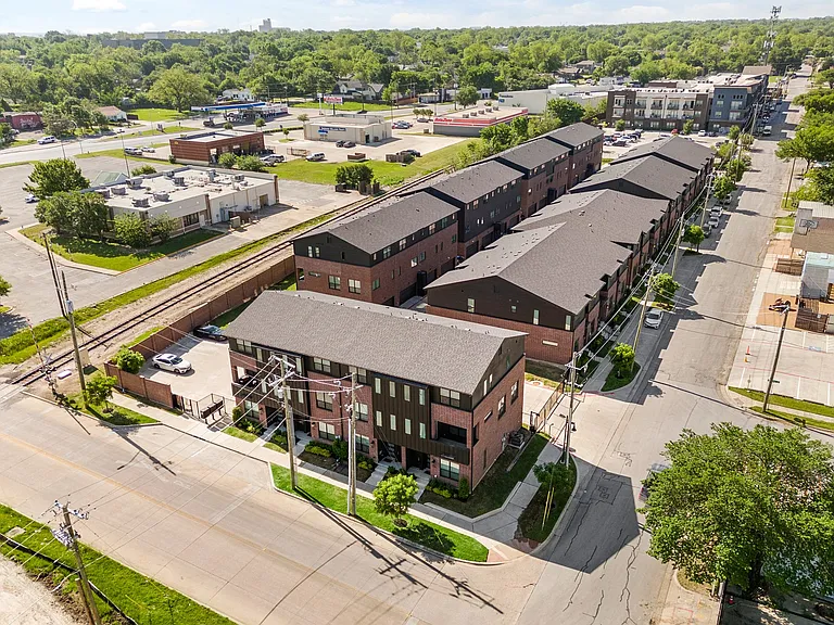 Exterior, aerial view of front of the townhome with street parking in front for tenants or guests. Additional tenant parking in the gated area is on the right.