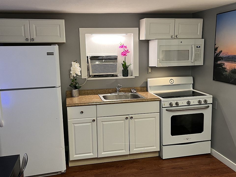 Full kitchen with refrigerator, glass top range, and microwave.