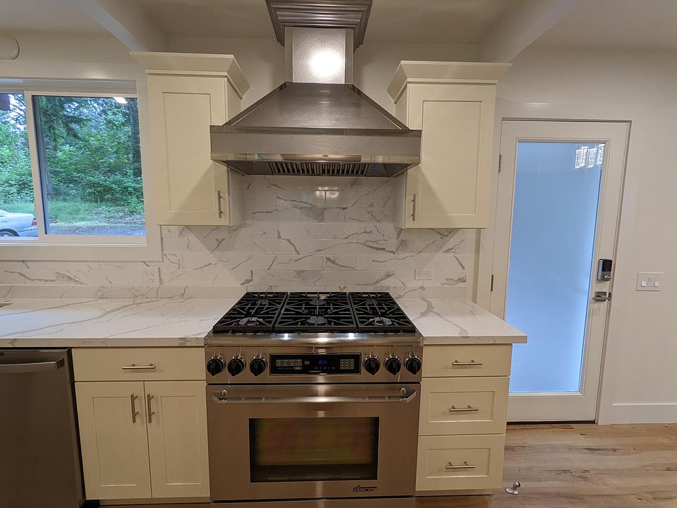 Kitchen with 36 in Dacor gas range and convection oven, SS hood, and carrara marble quartz countertops