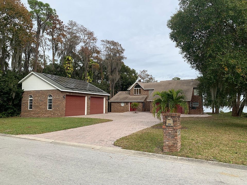 Front view, plenty of parking, attached 2 car garage, detached 4 car garage with car lift and solar panels. Lake Tarpon in background.