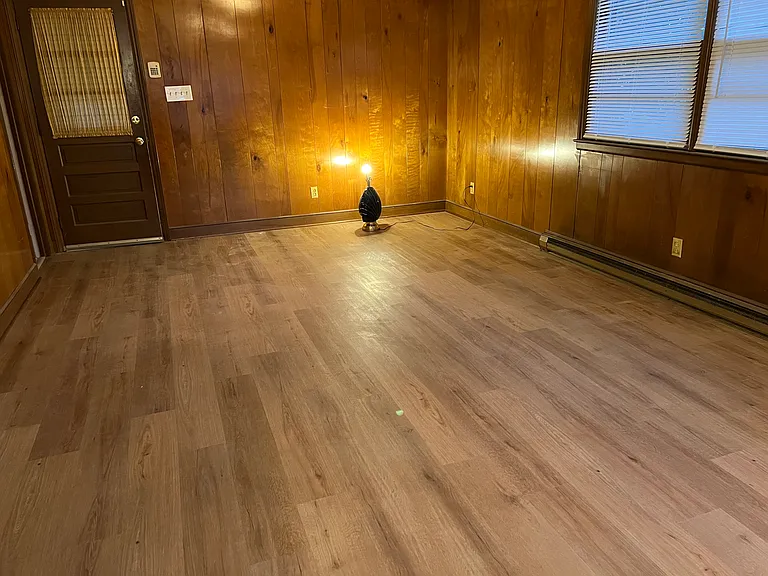 Large paneled den with just installed Luxury Vinyl Plank. Half bath near door. Side entrance to carport. New lighting being installed.