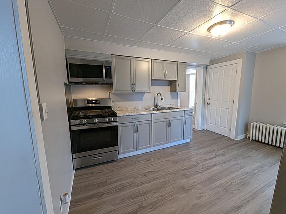Kitchen with cabinets, stove, microwave and vent