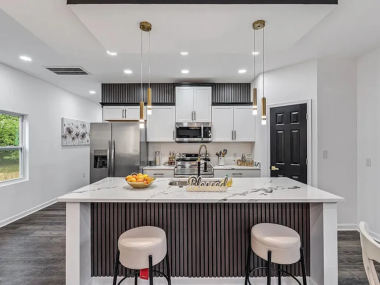 Spacious kitchen with a large waterfall island, bar seating, and stainless-steel appliances plus ample cabinet storage.