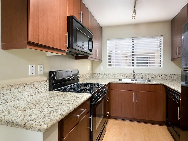 Classic Package I kitchen with chestnut cabinetry, beige speckled granite countertops, black appliances, and hard surface flooring