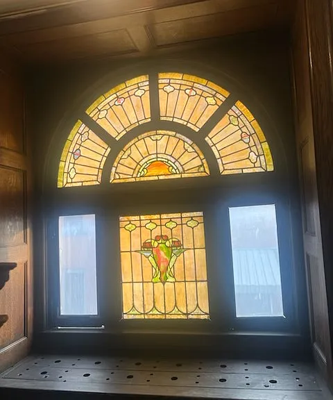 Beautiful original stained-glass window surrounded by rich natural woodwork, giving the property distinctive historic charm and craftsmanship.