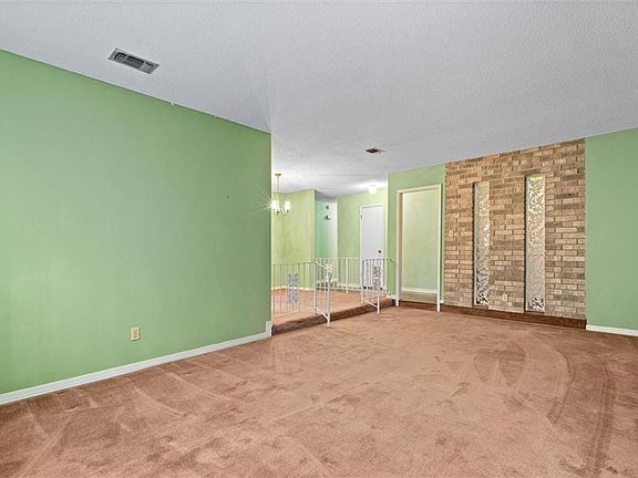 Carpeted empty room featuring a chandelier, a textured ceiling, visible vents, and baseboards