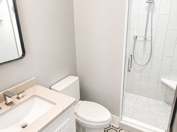 Bathroom with full size shower with tempered glass and built in seating.