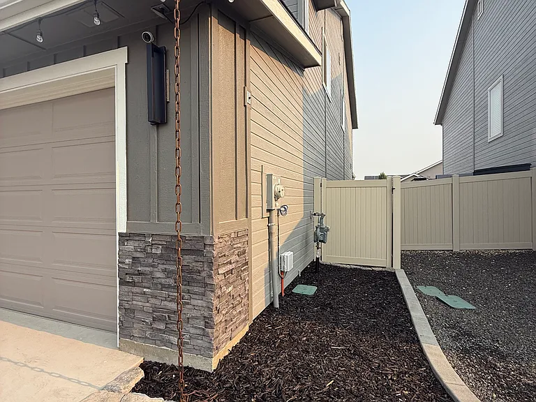 Side view of the home showing the garage, stone accent, and private side yard with fencing.