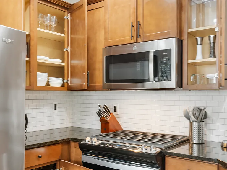 Kitchen is stocked with pots and pans, mixing bowls, measuring cups, baking trays, dishes, utensils, etc