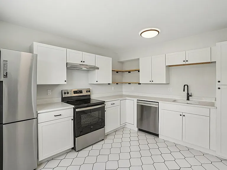 Contemporary kitchen with sleek stainless steel appliances, pristine white cabinetry, and elegant hexagonal floor tiles.