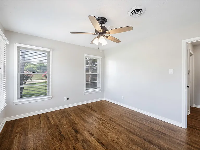 Unfurnished room featuring dark wood-type flooring and ceiling fan