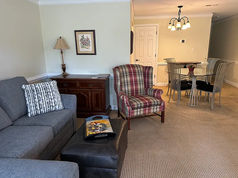 Living room with queen sleeper and chaise lounge, leather ottoman, wing chair.